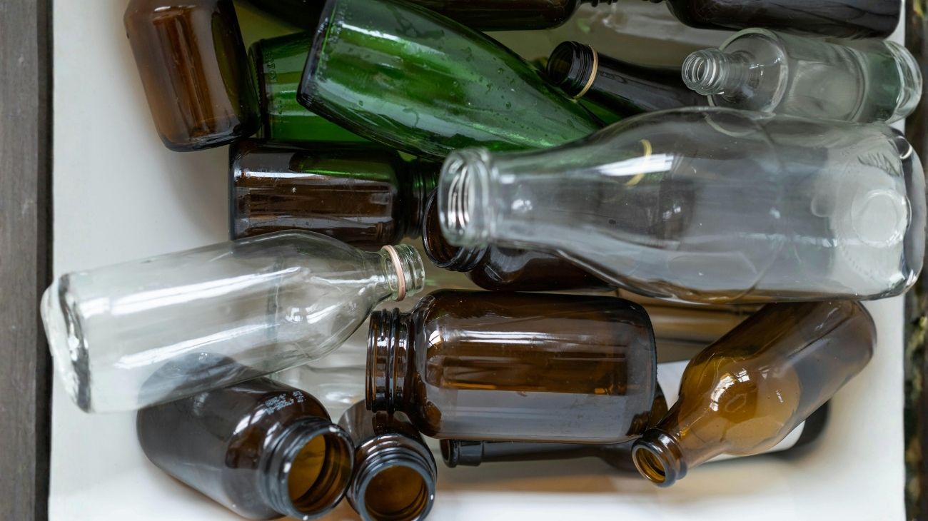 Collection of glass bottles and jars being sorted for recycling, representing the glass recycling process.
